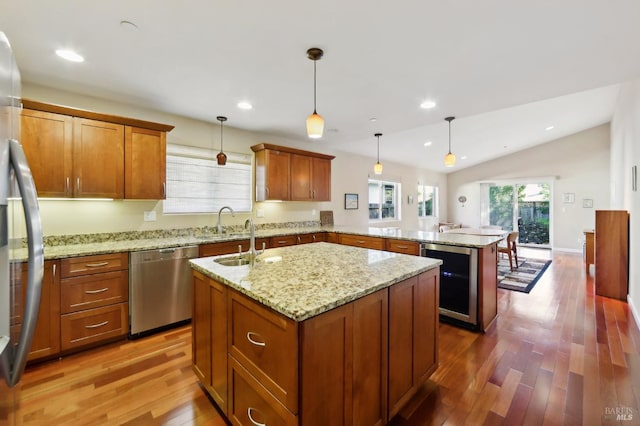 kitchen with pendant lighting, stainless steel appliances, kitchen peninsula, and a kitchen island with sink