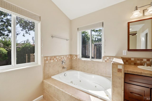 bathroom featuring a relaxing tiled tub, lofted ceiling, and vanity