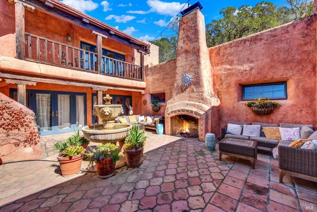 view of patio / terrace with a balcony and an outdoor living space with a fireplace