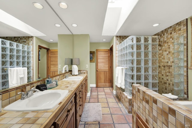 bathroom with a tile shower, vanity, and a skylight