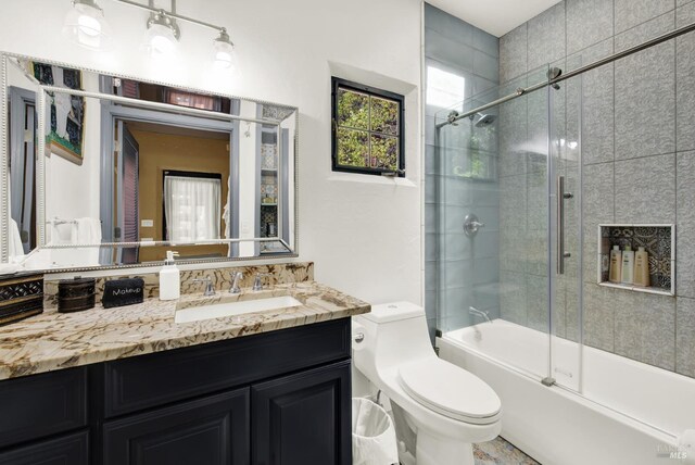 full bathroom featuring enclosed tub / shower combo, vanity, and toilet