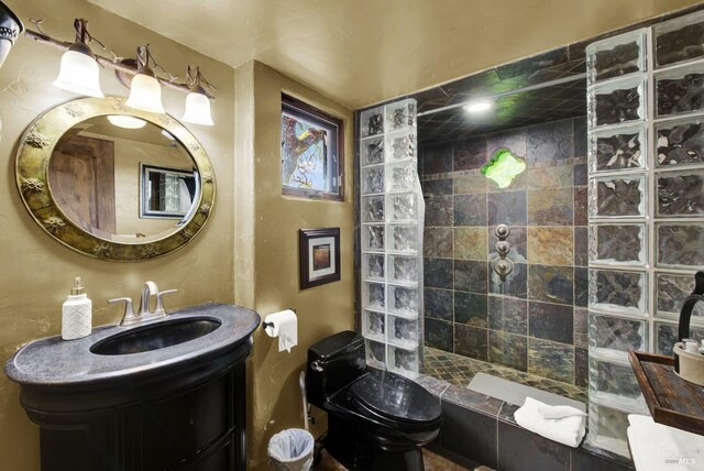 bathroom featuring vanity, toilet, and tiled shower