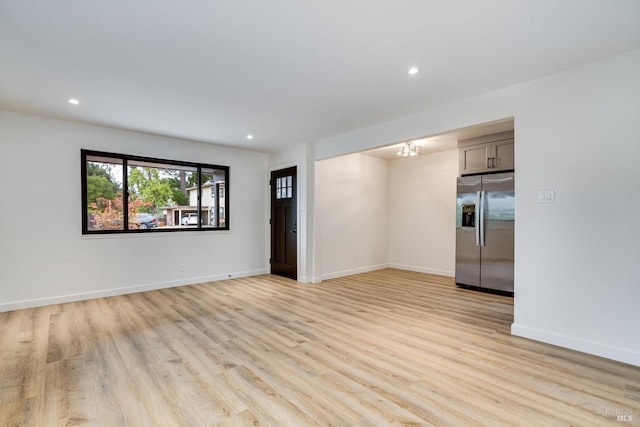 empty room with light wood-type flooring and a chandelier