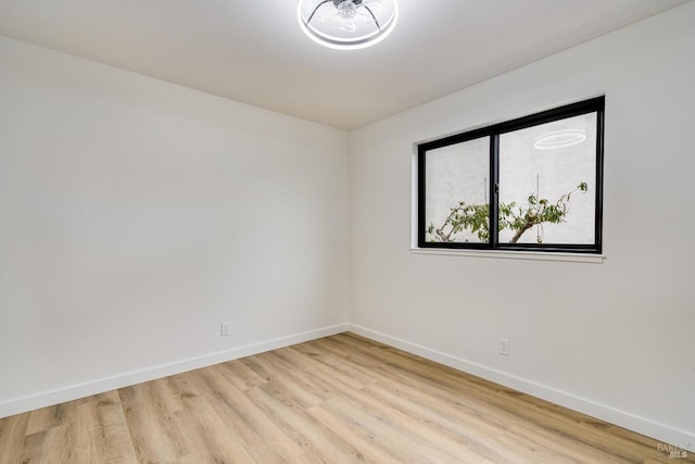 unfurnished room with light wood-style flooring and baseboards