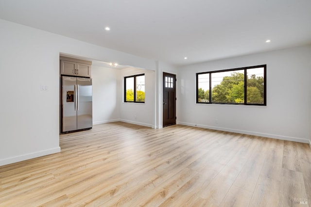 spare room with baseboards, recessed lighting, and light wood finished floors