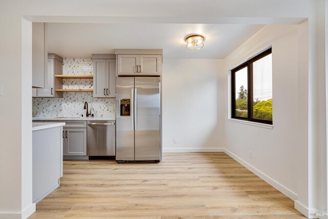 kitchen featuring light countertops, stainless steel appliances, open shelves, light wood-style floors, and gray cabinets