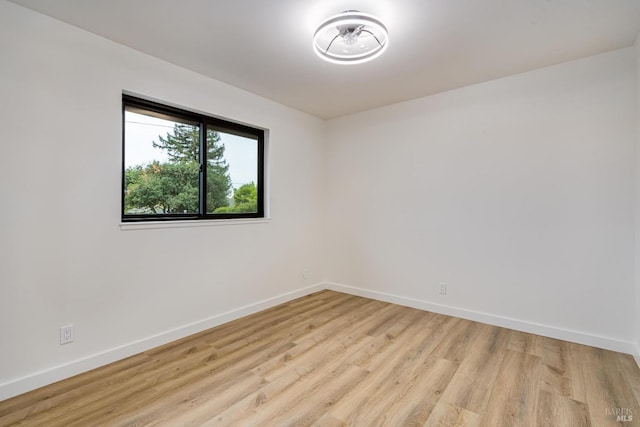 spare room with baseboards and light wood finished floors