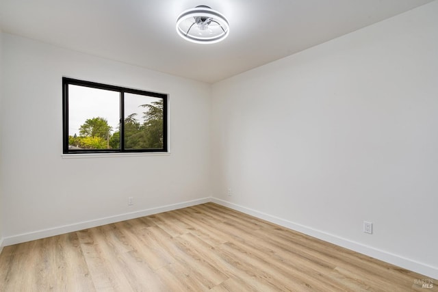empty room with baseboards and light wood-type flooring