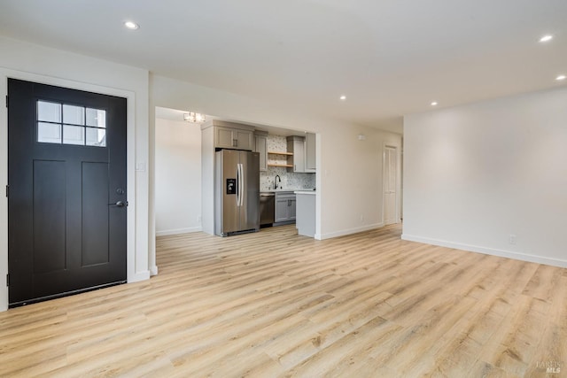 unfurnished living room with a sink, baseboards, recessed lighting, and light wood-type flooring