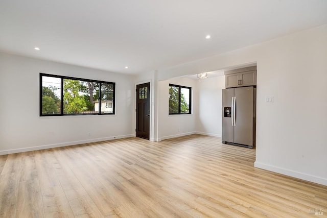 empty room with recessed lighting, baseboards, light wood-style floors, and a wealth of natural light