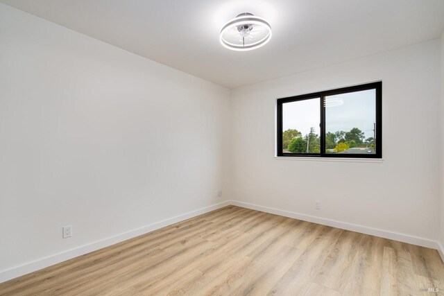 empty room featuring baseboards and light wood-style flooring