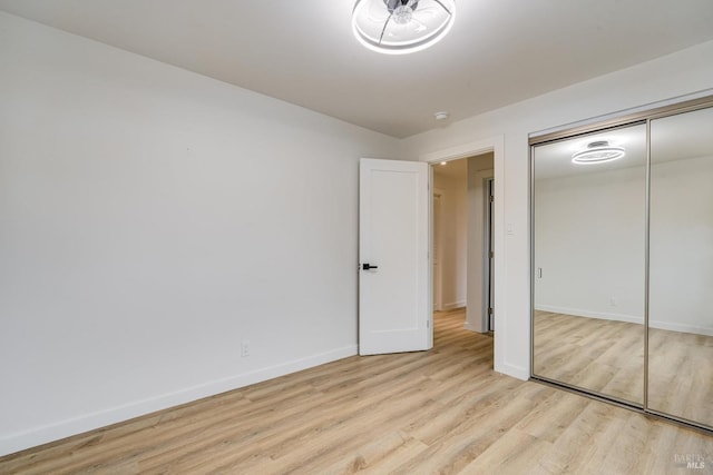 unfurnished bedroom with baseboards, a closet, and light wood-style floors