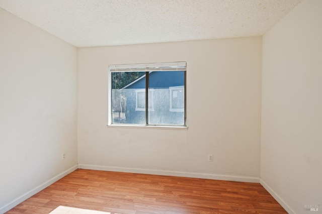 unfurnished room featuring light wood-type flooring and a textured ceiling