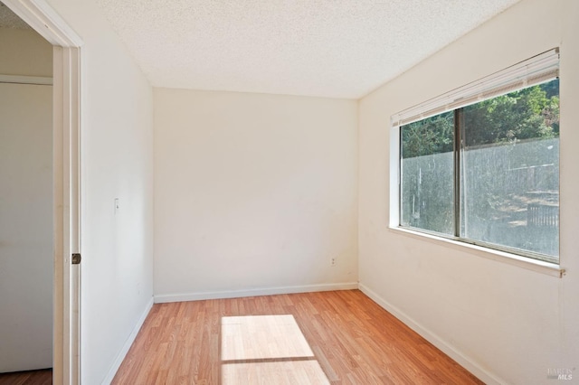 unfurnished room with a textured ceiling and light hardwood / wood-style floors