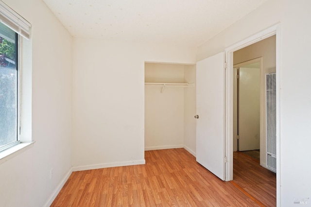 unfurnished bedroom with light wood-type flooring and a closet