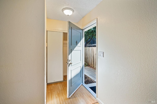 hallway with a textured ceiling and hardwood / wood-style floors