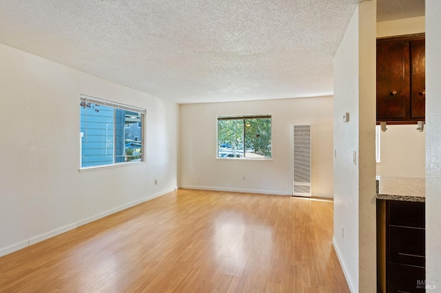 unfurnished living room with light wood-type flooring and a textured ceiling