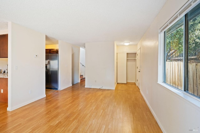 unfurnished room with a textured ceiling and light hardwood / wood-style flooring