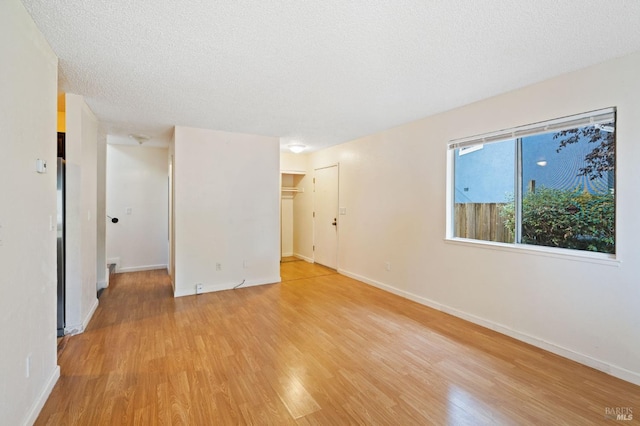 unfurnished room with light wood-type flooring and a textured ceiling