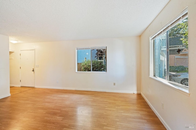 unfurnished room featuring light wood-type flooring, a healthy amount of sunlight, and a textured ceiling