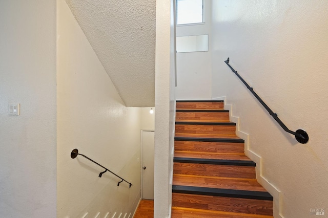 stairs featuring a textured ceiling and wood-type flooring