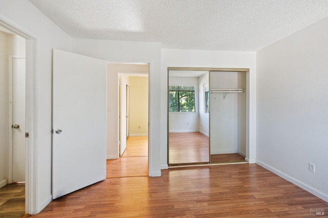 unfurnished bedroom featuring a textured ceiling, wood-type flooring, and a closet