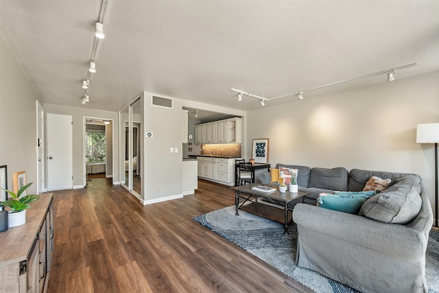 living area featuring dark wood finished floors, track lighting, visible vents, and baseboards