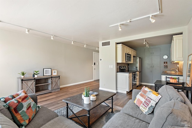 living area with rail lighting, baseboards, wood finished floors, and visible vents