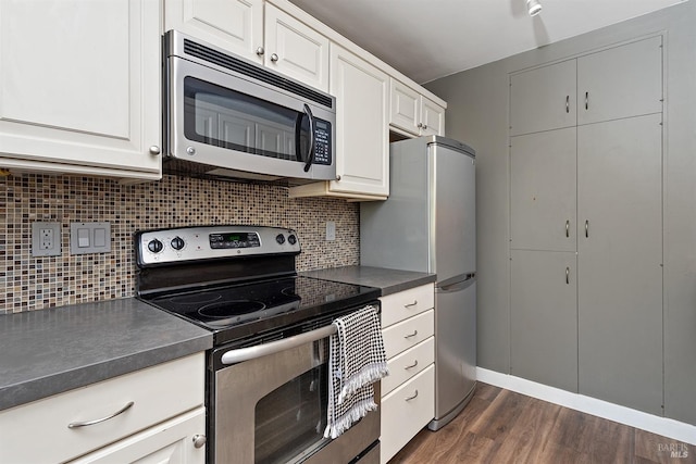 kitchen featuring dark countertops, backsplash, appliances with stainless steel finishes, and dark wood finished floors