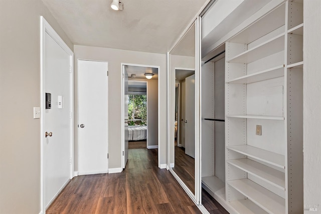 corridor featuring baseboards and wood finished floors