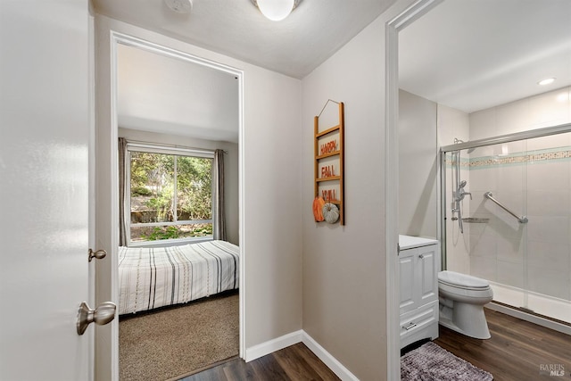 bathroom featuring a shower stall, wood finished floors, vanity, baseboards, and toilet