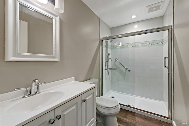 full bathroom featuring wood finished floors, visible vents, toilet, vanity, and a stall shower