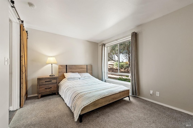 bedroom with a barn door, baseboards, and carpet flooring