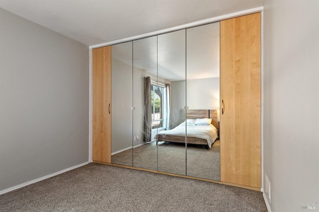 unfurnished bedroom with baseboards, carpet floors, and a closet