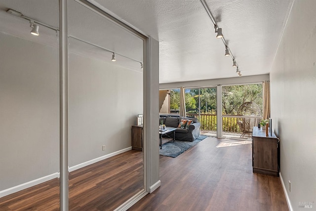 doorway featuring baseboards, wood finished floors, and rail lighting