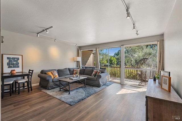 living room with a textured ceiling, rail lighting, and dark wood-style flooring