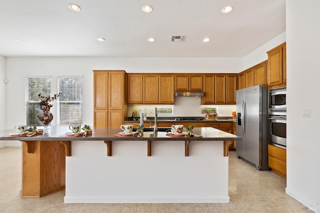 kitchen featuring a kitchen bar, a center island with sink, and stainless steel appliances