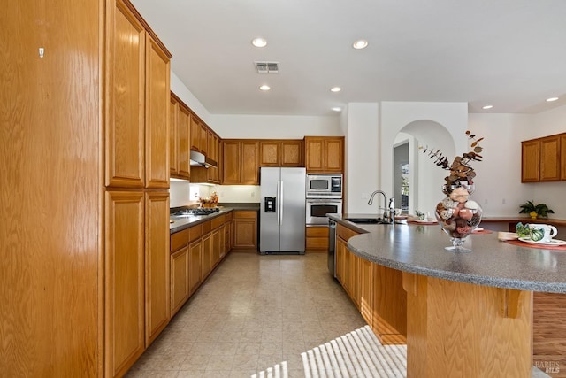 kitchen with a kitchen breakfast bar, a kitchen island with sink, sink, and stainless steel appliances