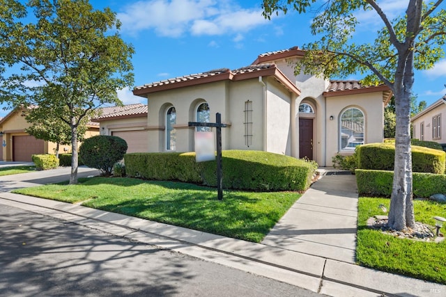 mediterranean / spanish house with a garage and a front lawn