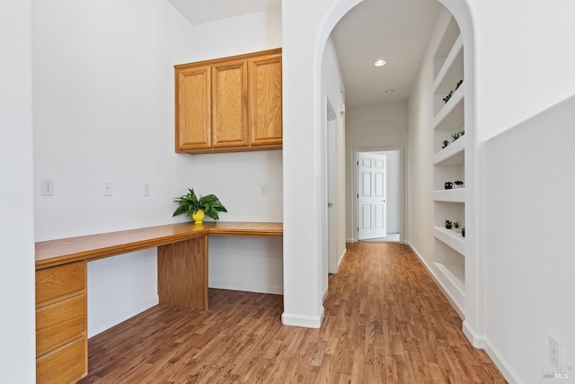 corridor featuring light wood-type flooring and built in features