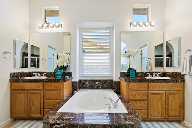 bathroom featuring vanity and tiled bath