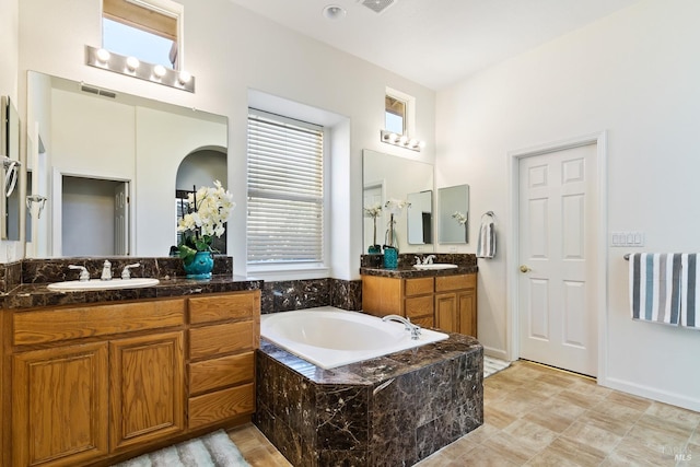 bathroom featuring vanity and tiled bath