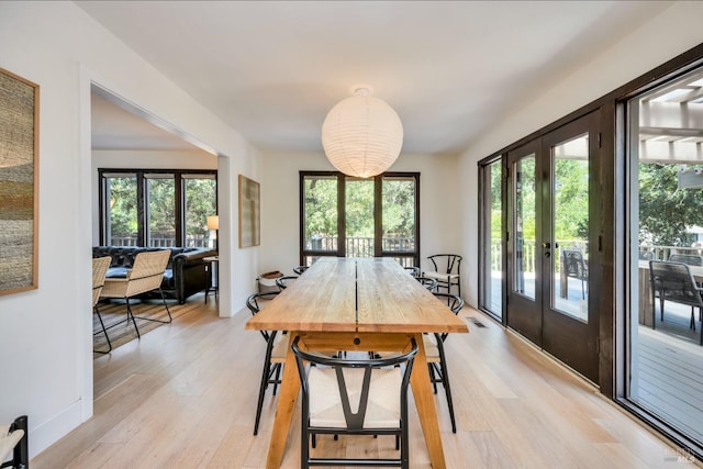 dining room with french doors, light wood-type flooring, and a healthy amount of sunlight