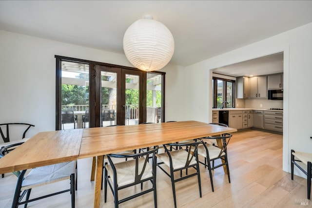 dining area featuring light wood-type flooring, sink, french doors, and plenty of natural light