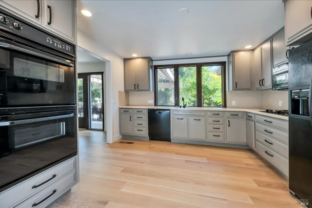 kitchen featuring a wealth of natural light, black appliances, and light hardwood / wood-style floors