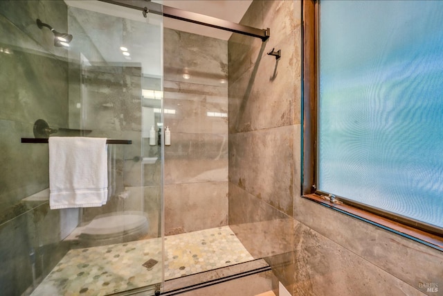 bathroom featuring a shower with shower door and toilet