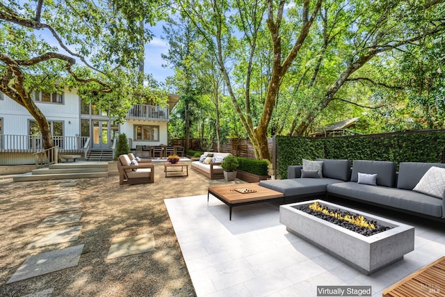 view of patio featuring a balcony and an outdoor living space with a fire pit