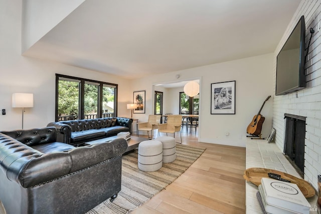 living room with light hardwood / wood-style floors and a brick fireplace