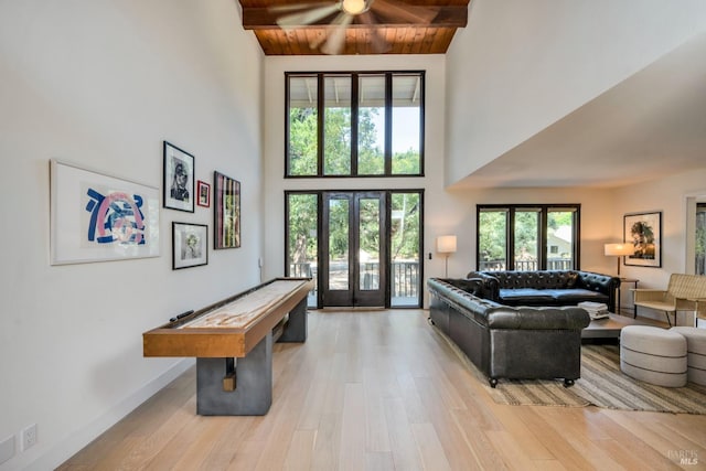 living room with high vaulted ceiling, beam ceiling, ceiling fan, and light hardwood / wood-style flooring