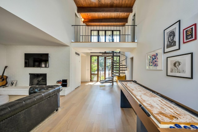 interior space featuring wood ceiling, light wood-type flooring, beamed ceiling, a fireplace, and a towering ceiling